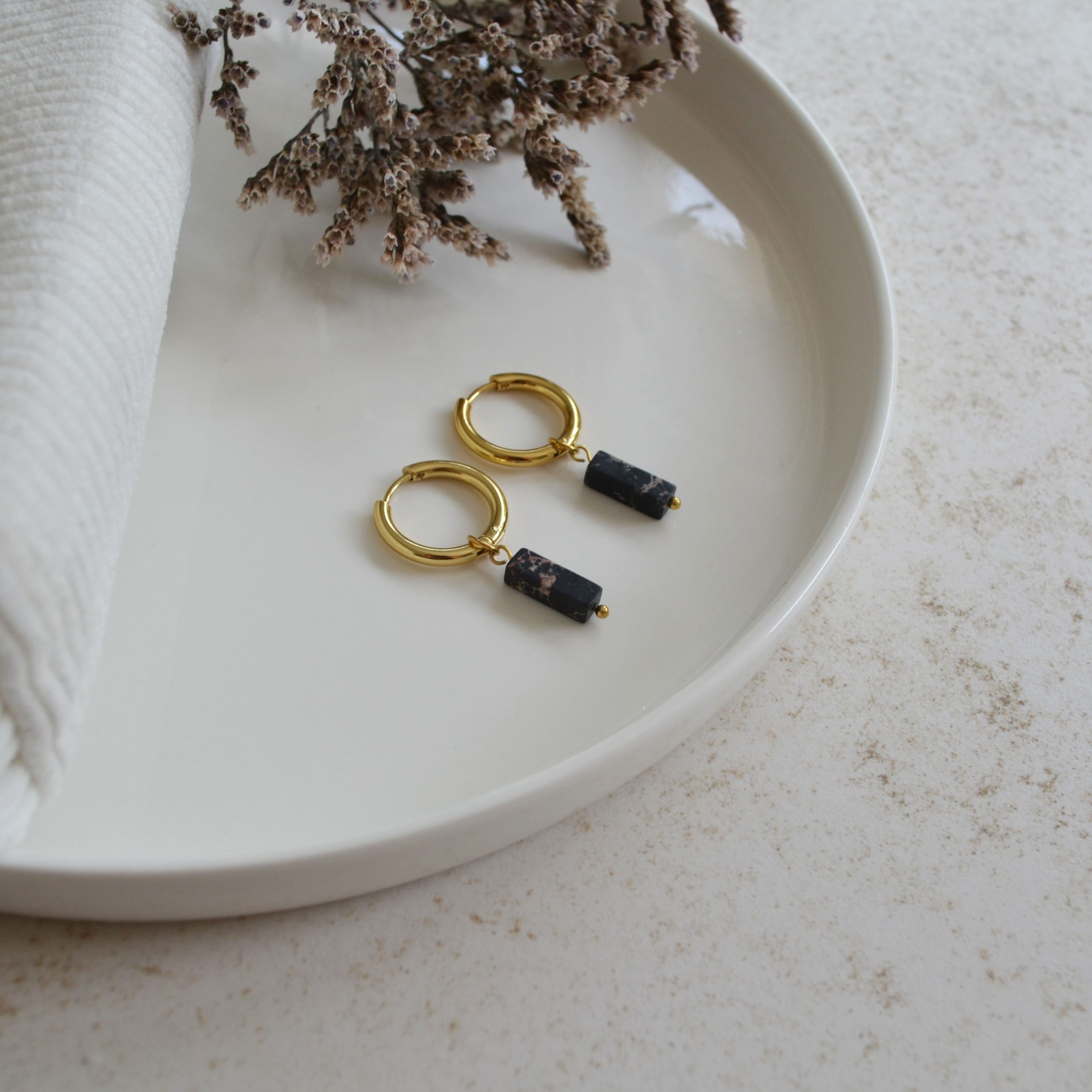 Boucles d'oreilles en acier inoxydable avec mini créoles dorées ornées d'un pendentif en forme de rectangle noir.