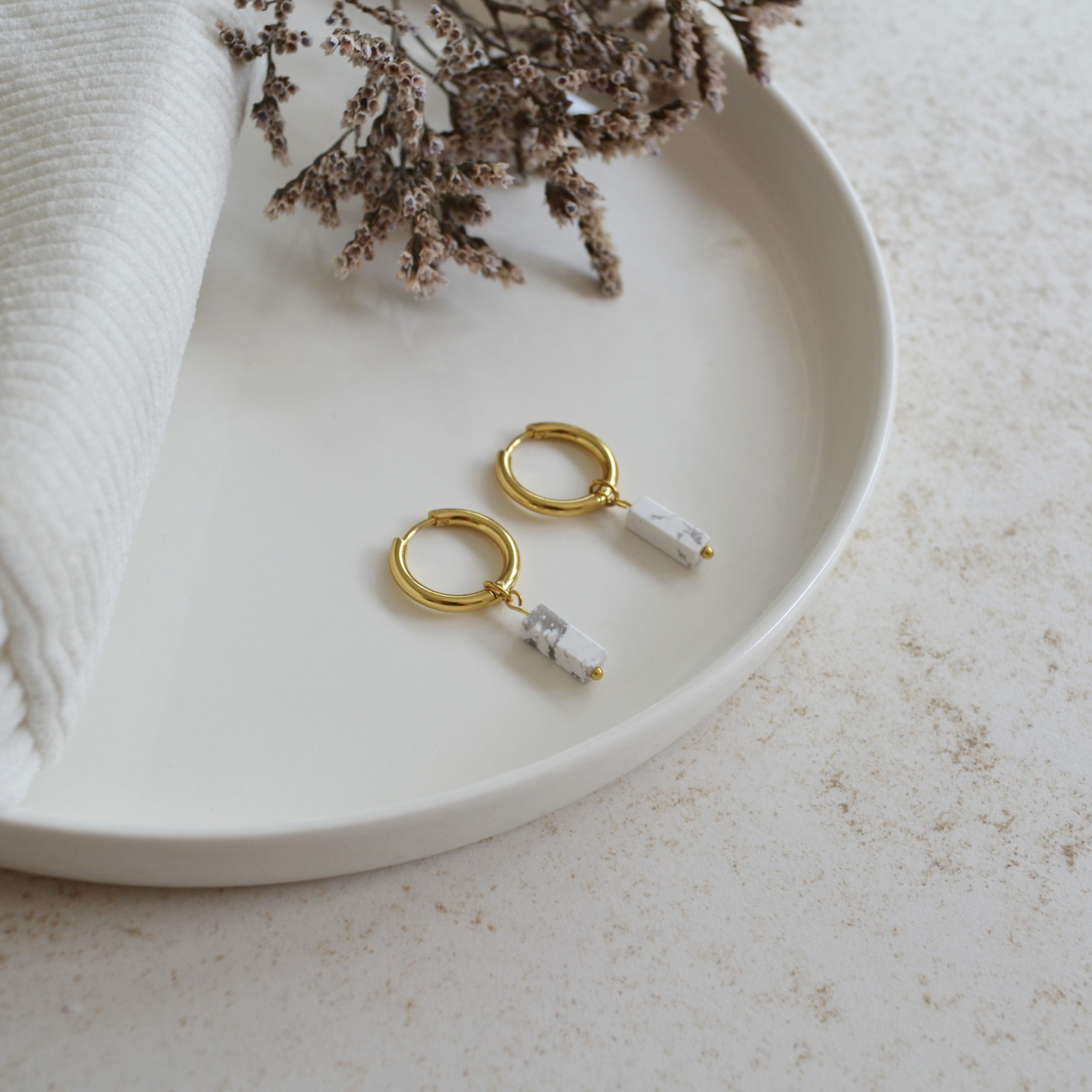 Boucles d'oreilles en acier inoxydable avec mini créoles dorées ornées d'un pendentif en forme de rectangle blanc et gris.