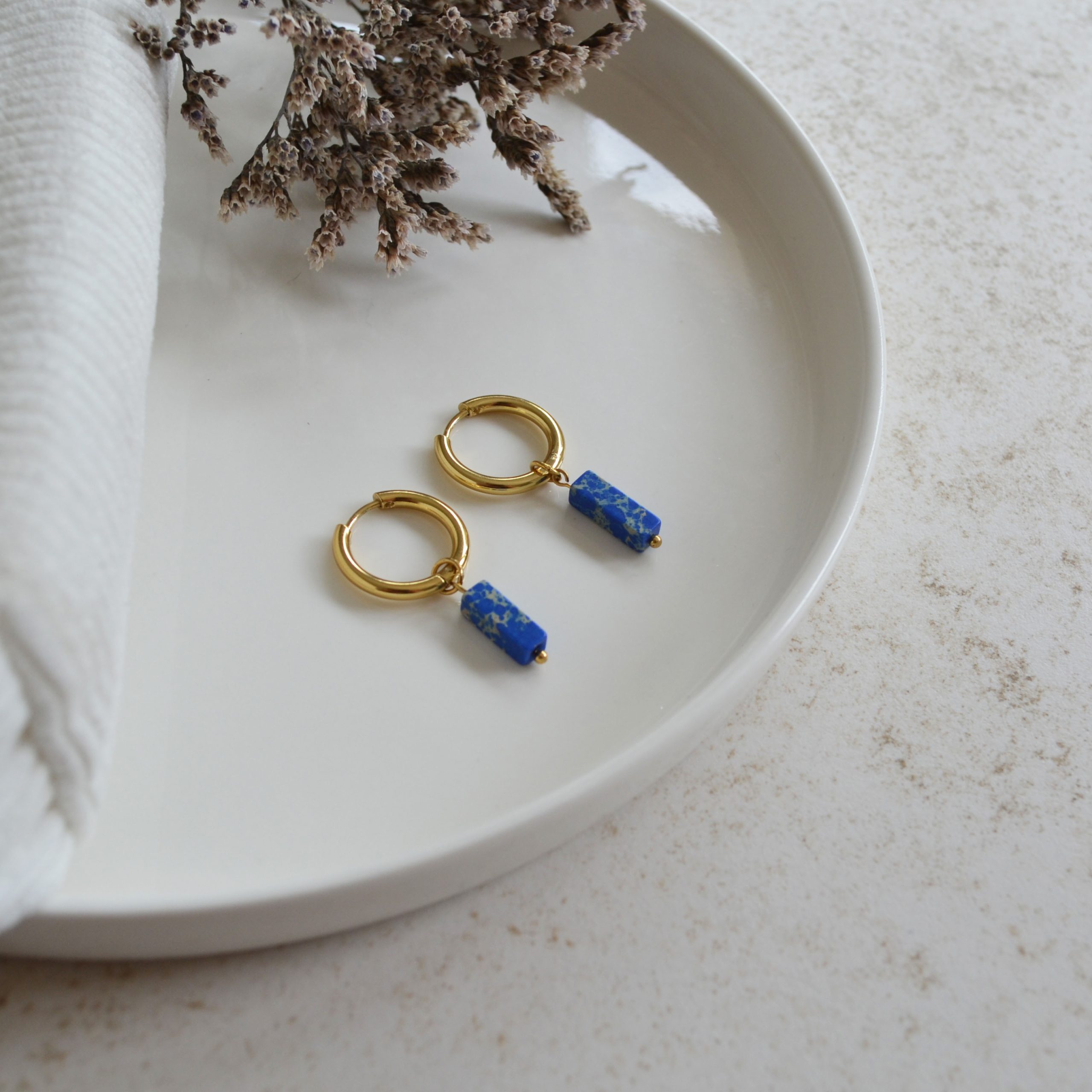 Boucles d'oreilles en acier inoxydable avec mini créoles dorées ornées d'un pendentif en forme de rectangle bleu.