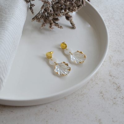 Boucles d'oreilles en acier inoxydable avec puces ornées de pendentifs dorés et blancs en forme de coquillage esprit vacances à la plage.