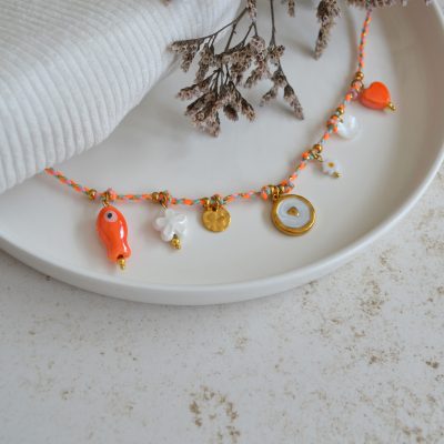 Collier en acier inoxydable avec chaine en cordon orange orné de sept pendentifs dorés et orange esprit estival.