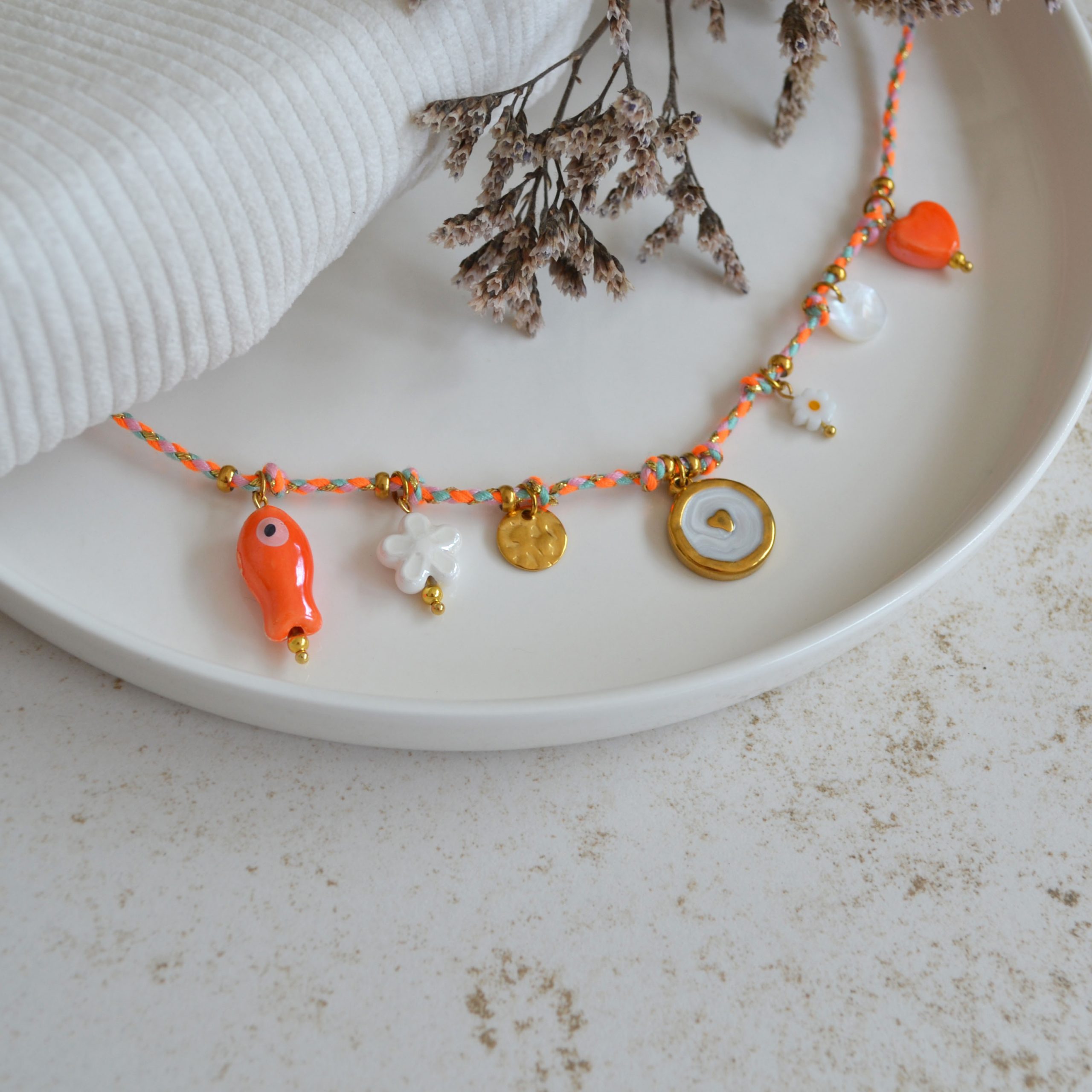 Collier en acier inoxydable avec chaine en cordon orange orné de sept pendentifs dorés et orange esprit estival.