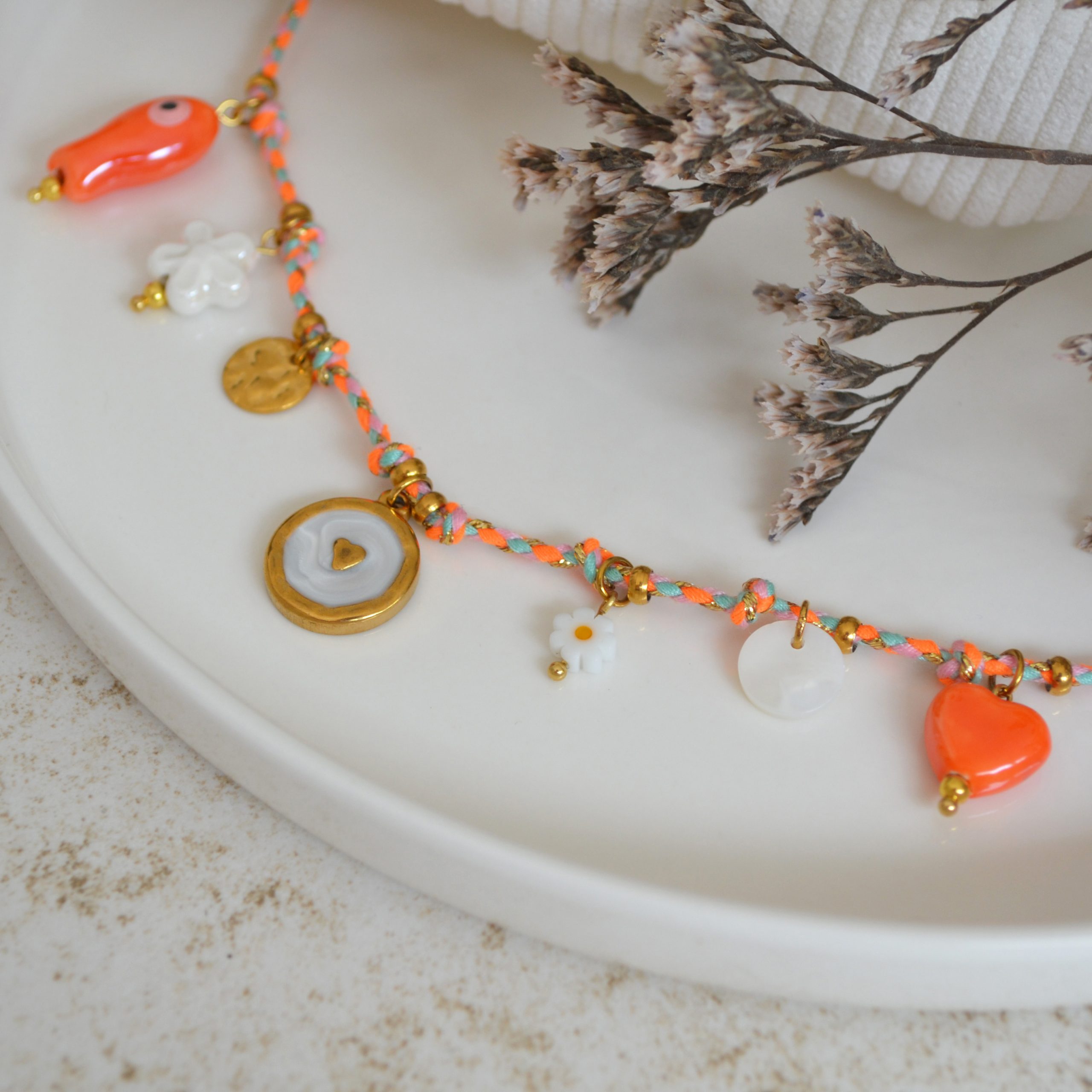Collier en acier inoxydable avec chaine en cordon orange orné de sept pendentifs dorés et orange esprit estival.
