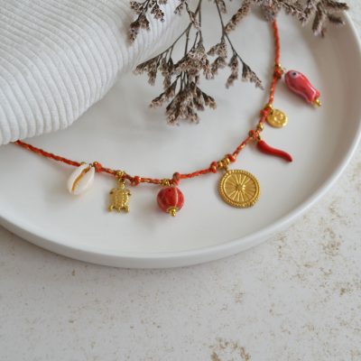Collier en acier inoxydable avec chaine en cordon rouge orné de sept pendentifs dorés et rouges esprit vacances.