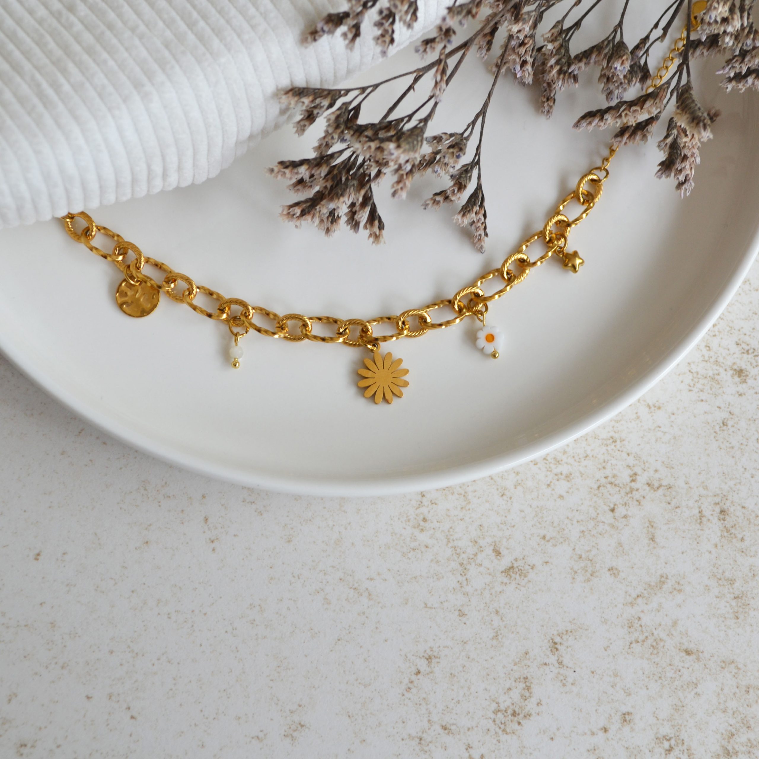 Bracelet en acier inoxydable avec maxi maillons orné de cinq pendentifs dorés et blancs esprit printemps fleuri.