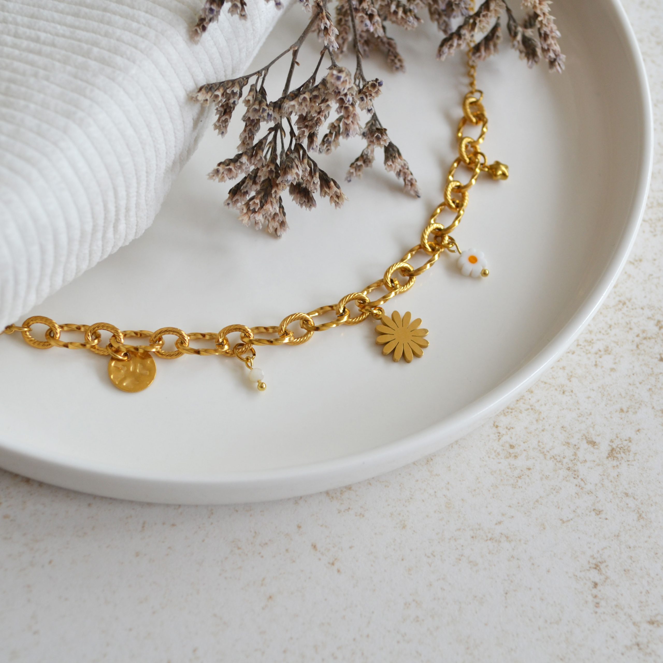 Bracelet en acier inoxydable avec maxi maillons orné de cinq pendentifs dorés et blancs esprit printemps fleuri.