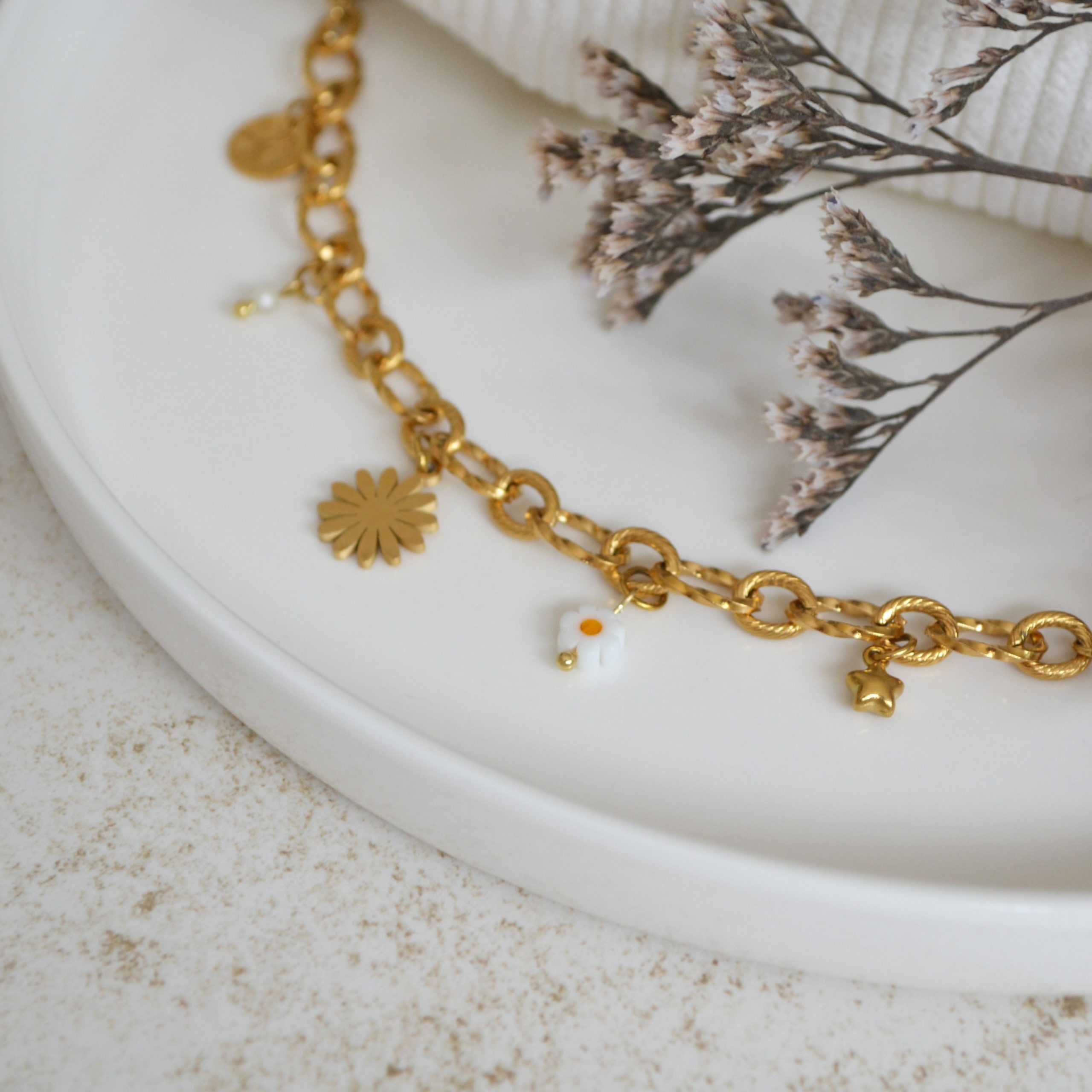 Bracelet en acier inoxydable avec maxi maillons orné de cinq pendentifs dorés et blancs esprit printemps fleuri.
