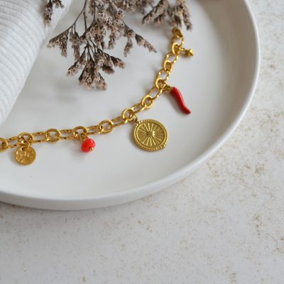 Bracelet en acier inoxydable avec maxi maillons orné de cinq pendentifs dorés et rouges.