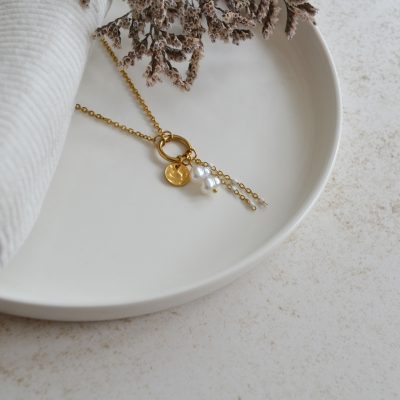Collier en acier inoxydable avec anneau orné de trois pendentifs dorés et blancs esprit élégant.