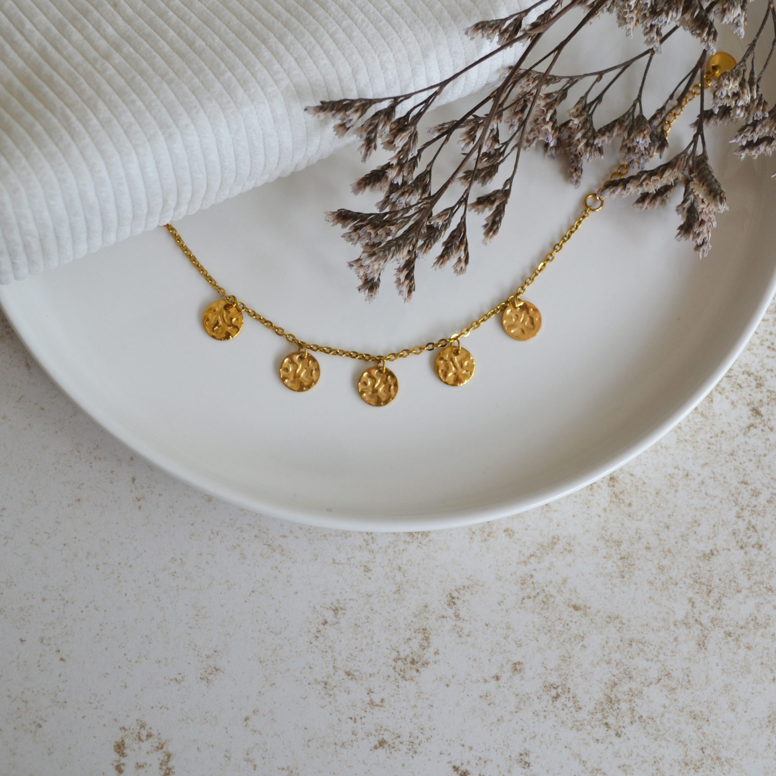 Bracelet en acier inoxydable avec chaine fine orné de cinq pendentifs ronds dorés à grains esprit élégant.