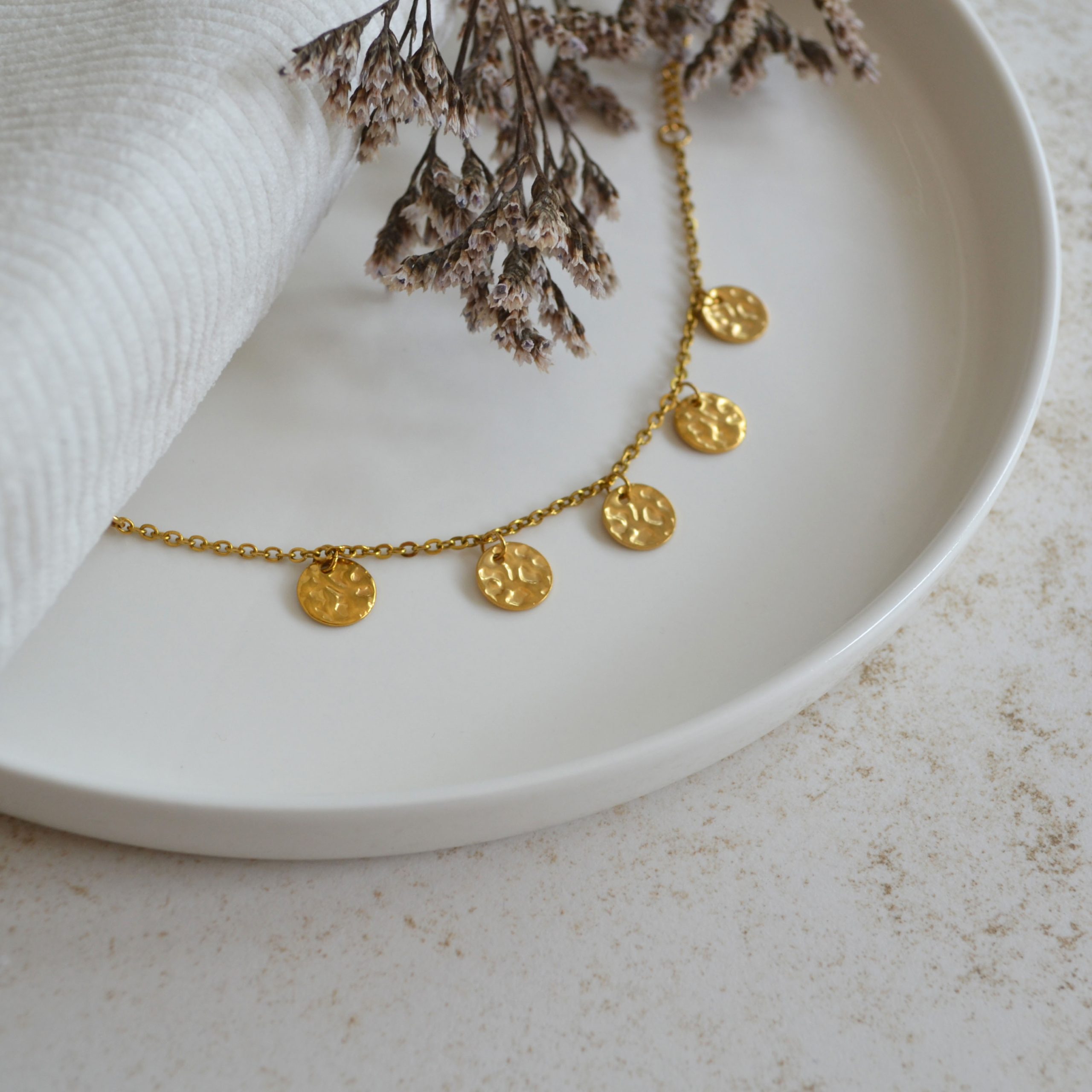 Bracelet en acier inoxydable avec chaine fine orné de cinq pendentifs ronds dorés à grains esprit élégant.