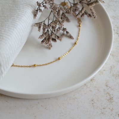Bracelet en acier inoxydable avec chaine fine orné de petits ronds dorés esprit élégant.