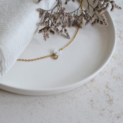 Bracelet en acier inoxydable avec chaine fine orné de pendentifs dorés et blanc esprit élégant.
