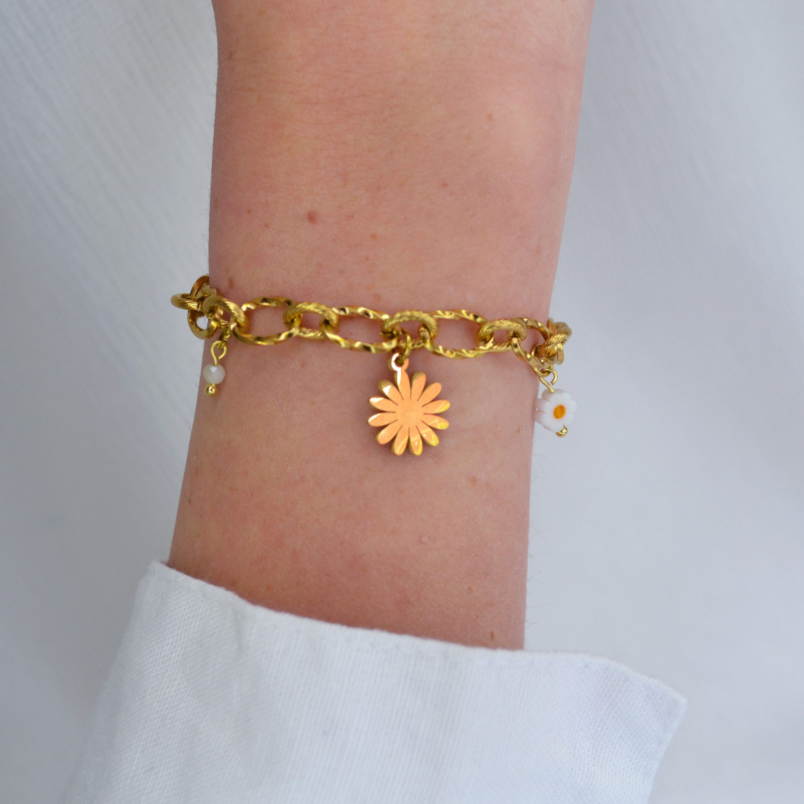 Bracelet en acier inoxydable avec maxi maillons orné de cinq pendentifs dorés et blancs esprit printemps fleuri.