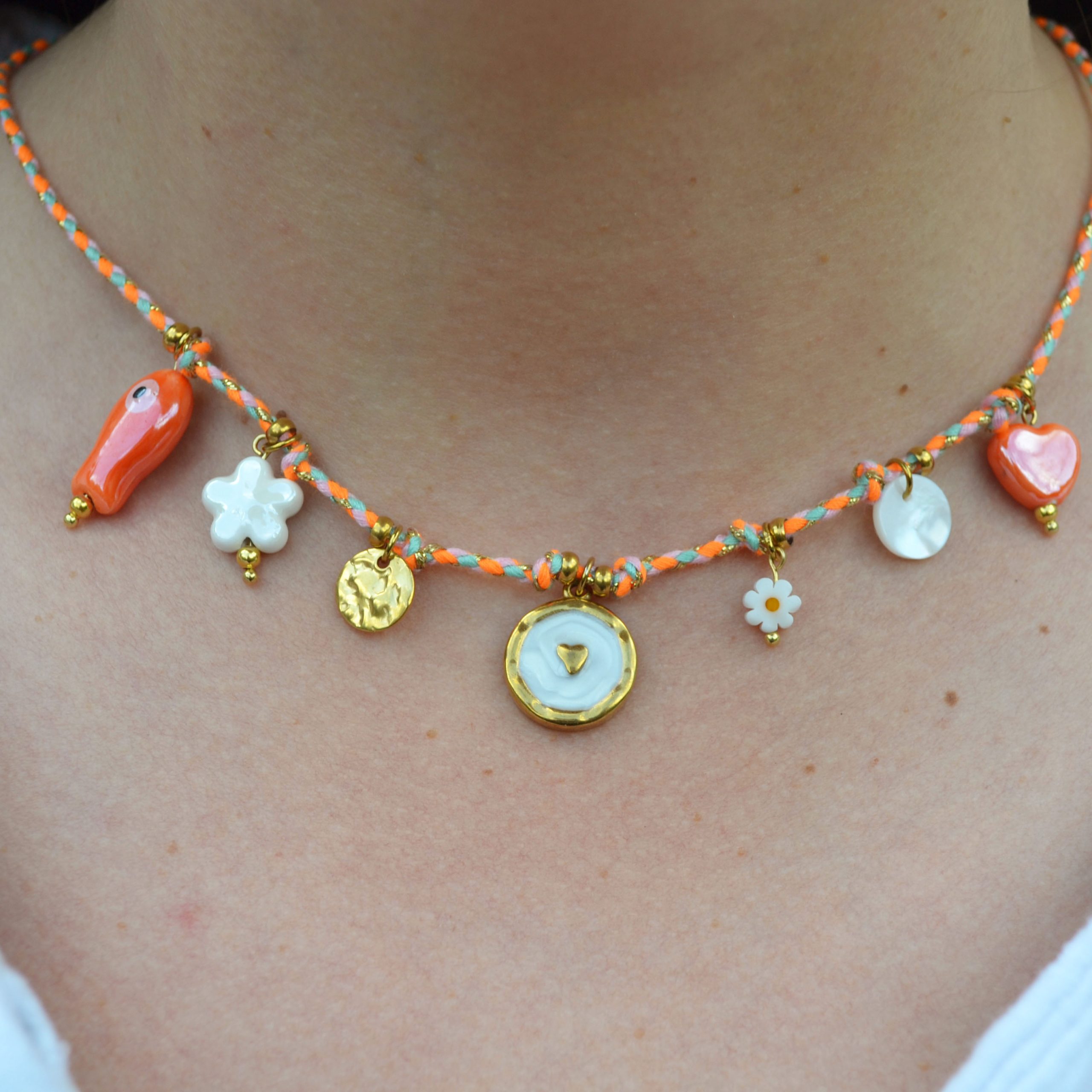 Collier en acier inoxydable avec chaine en cordon orange orné de sept pendentifs dorés et orange esprit estival.