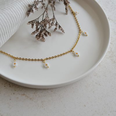 Collier en acier inoxydable avec chaine fine dorée orné de cinq pendentifs marguerites blanches esprit floral.