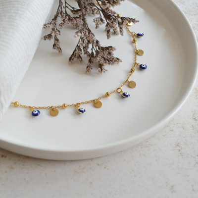 Bracelet de cheville en acier inoxydable avec chaine fine dorée ornée de pendentifs oeil bleu esprit vacances en Grèce.