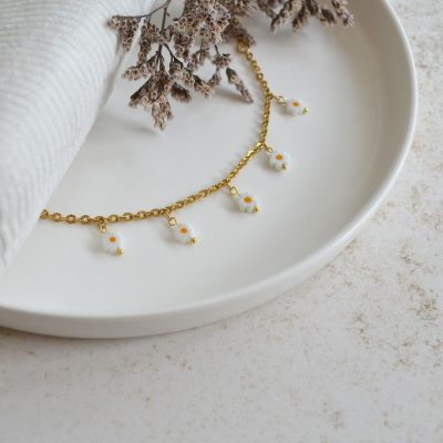 Bracelet en acier inoxydable avec chaine fine dorée orné de cinq pendentifs marguerites blanches esprit floral.